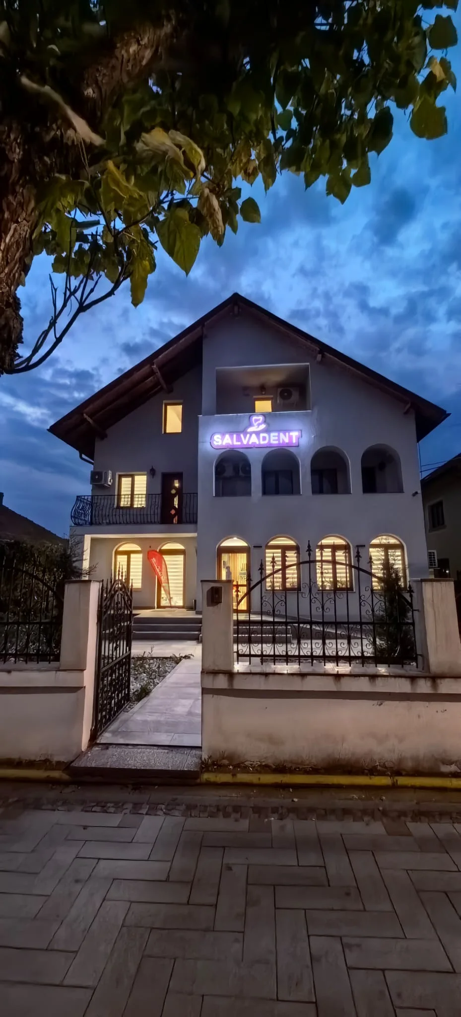 Fațada Clinicii SalvaDent din Curtea de Argeș, seara, cu firma luminată deasupra intrării